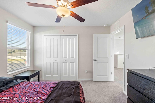 carpeted bedroom with ceiling fan, a textured ceiling, and a closet