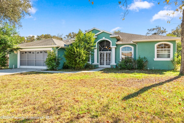 ranch-style home with a front lawn, a garage, and french doors