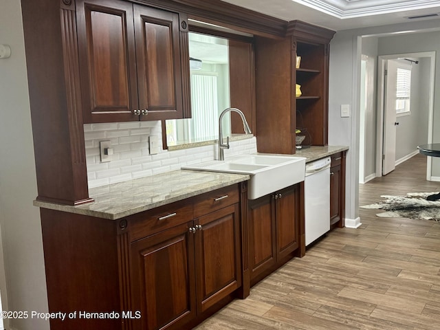 kitchen with sink, light hardwood / wood-style flooring, dishwasher, tasteful backsplash, and light stone countertops