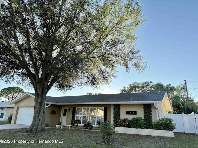 ranch-style house featuring a garage and a front lawn