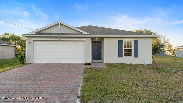 single story home with a garage and a front lawn