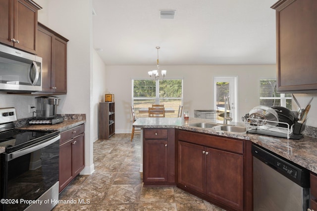 kitchen with sink, stainless steel appliances, an inviting chandelier, dark stone countertops, and decorative light fixtures