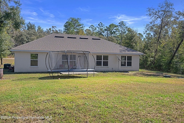 back of house with a yard and a trampoline