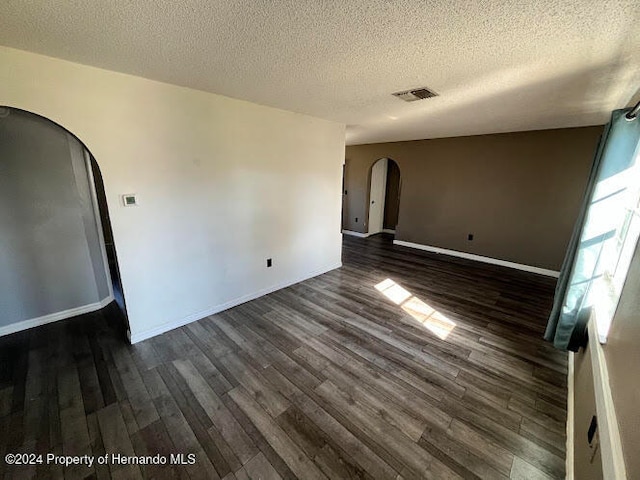 spare room featuring a textured ceiling and dark wood-type flooring