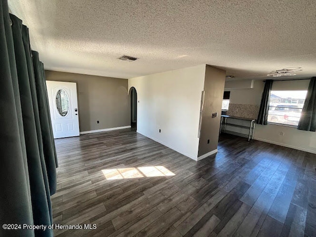 spare room with a textured ceiling and dark wood-type flooring