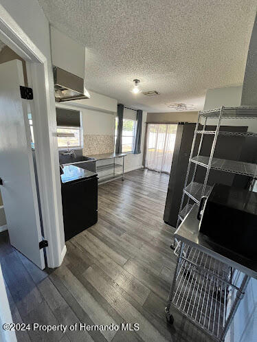 kitchen featuring a textured ceiling, white cabinets, and dark wood-type flooring