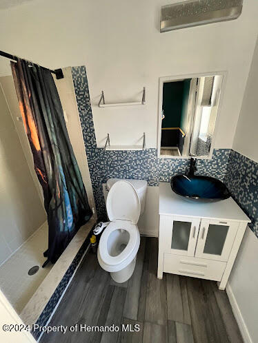 bathroom with hardwood / wood-style floors, vanity, toilet, and a shower with curtain