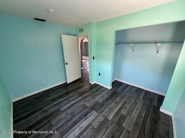 unfurnished bedroom featuring dark hardwood / wood-style floors, a textured ceiling, and a closet