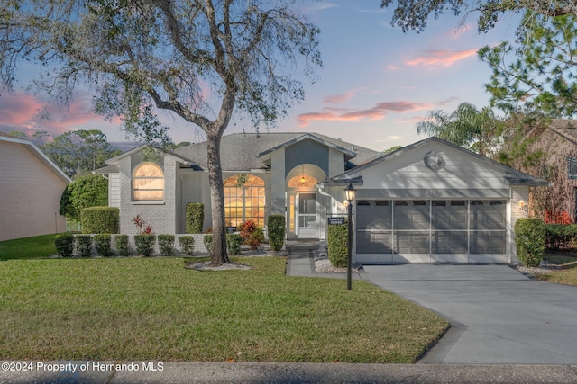 ranch-style home featuring a garage and a yard