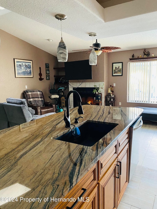 kitchen with dishwasher, sink, dark stone counters, and a textured ceiling