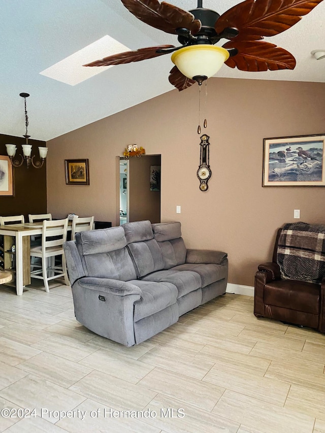 living room featuring lofted ceiling with skylight and ceiling fan with notable chandelier