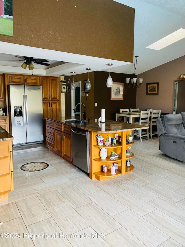 kitchen featuring ceiling fan with notable chandelier, stainless steel appliances, lofted ceiling with skylight, sink, and pendant lighting