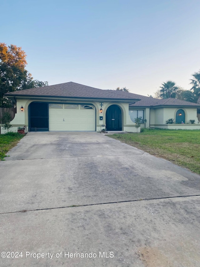 single story home with a garage and a front lawn