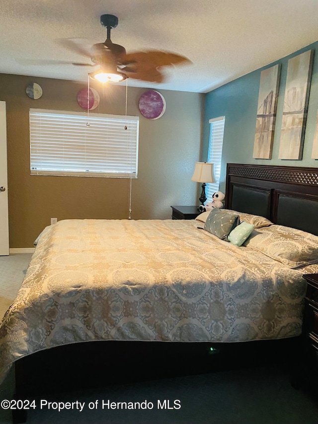 bedroom with a textured ceiling, carpet floors, and ceiling fan