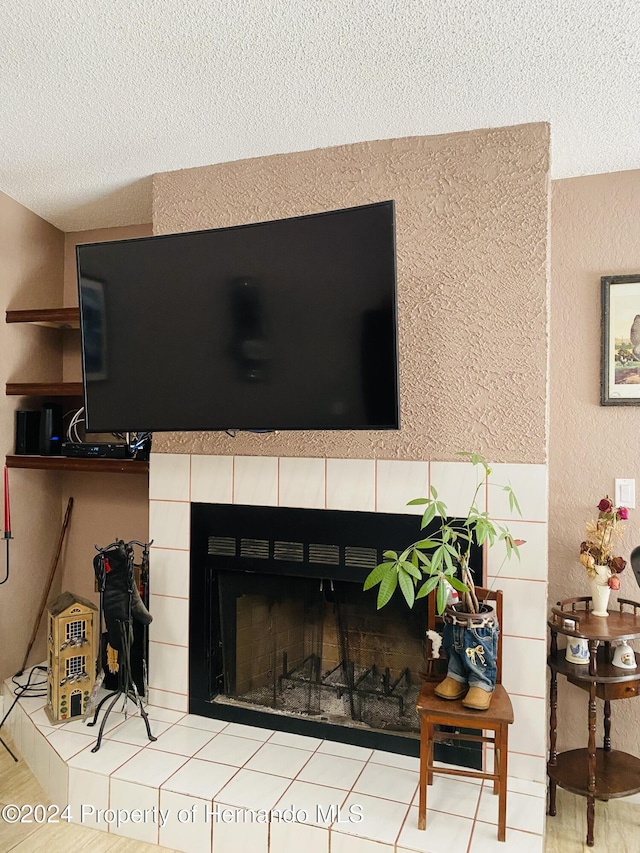 interior details featuring a tile fireplace and a textured ceiling