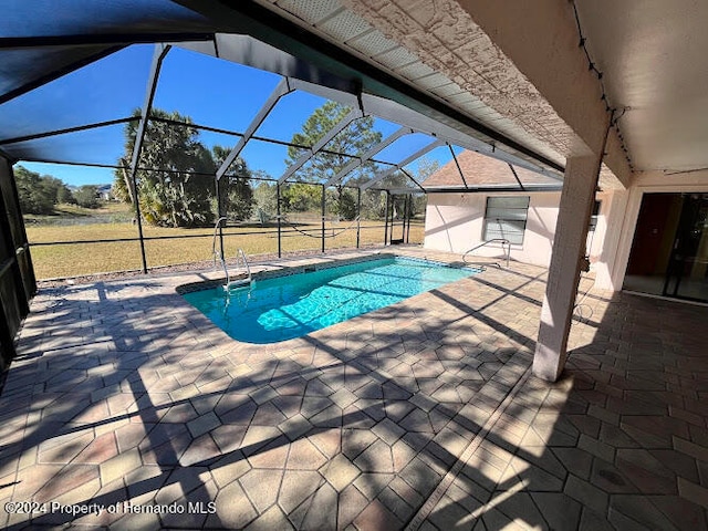 view of swimming pool with a patio area and a lanai