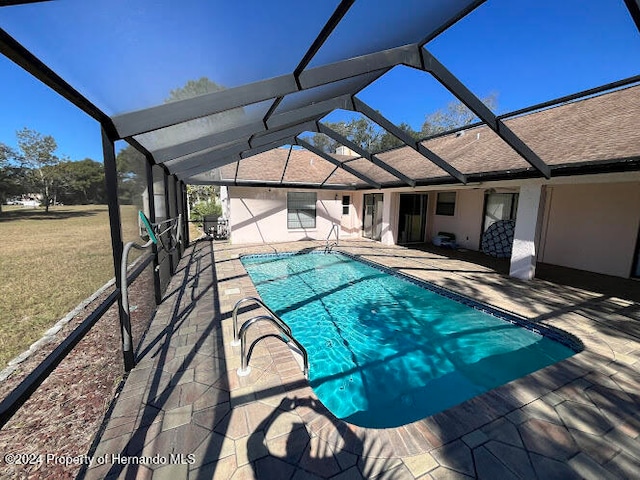 view of swimming pool featuring glass enclosure, a yard, and a patio