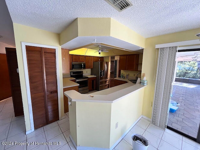 kitchen with kitchen peninsula, a textured ceiling, stainless steel appliances, ceiling fan, and sink