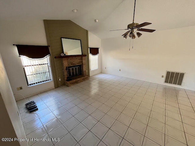 unfurnished living room featuring ceiling fan, light tile patterned floors, high vaulted ceiling, and a brick fireplace