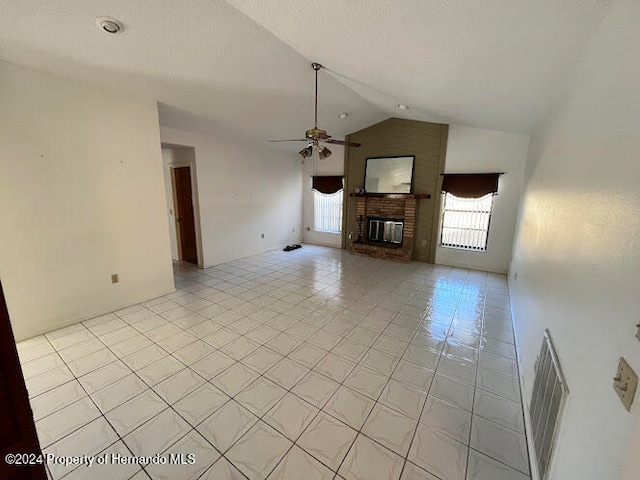 unfurnished living room featuring ceiling fan, a fireplace, light tile patterned floors, and lofted ceiling