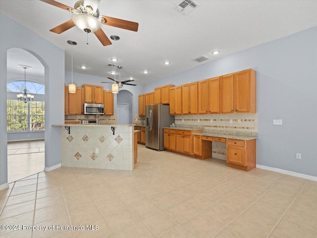 kitchen with light stone countertops, stainless steel appliances, tasteful backsplash, kitchen peninsula, and a kitchen bar