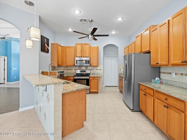 kitchen featuring decorative backsplash, light stone countertops, a textured ceiling, appliances with stainless steel finishes, and kitchen peninsula