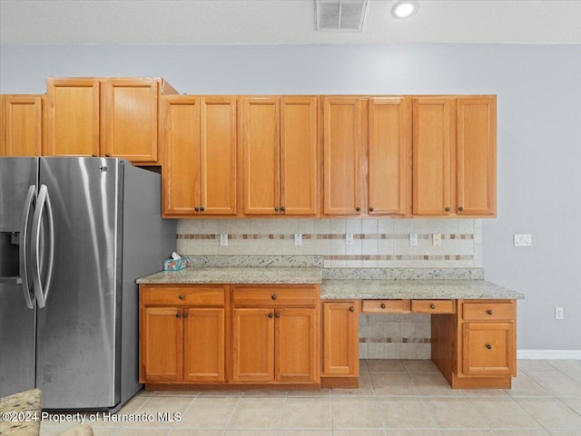 kitchen with light stone counters, stainless steel fridge with ice dispenser, backsplash, and light tile patterned floors