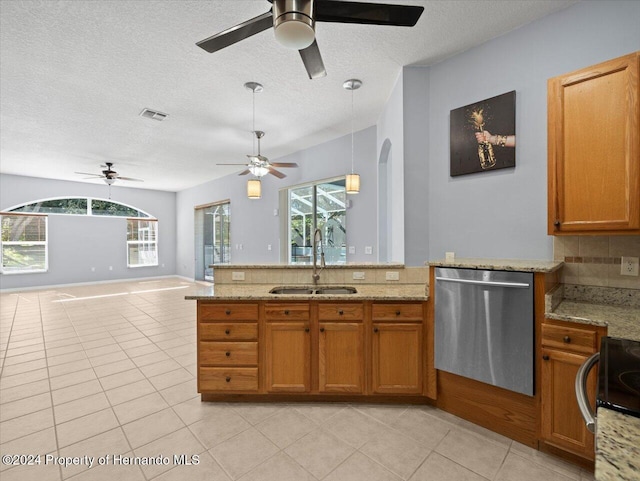 kitchen with tasteful backsplash, stainless steel dishwasher, a textured ceiling, sink, and light tile patterned floors