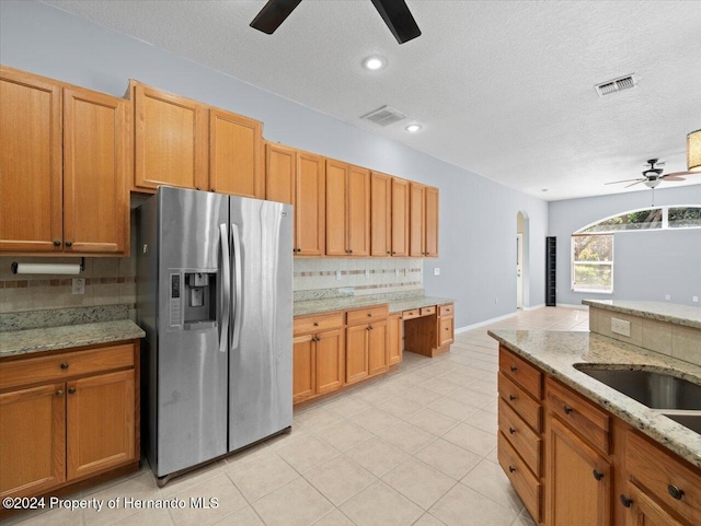 kitchen with decorative backsplash, stainless steel fridge, light stone counters, and ceiling fan