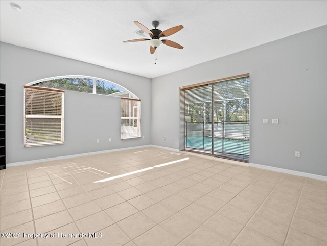 spare room featuring ceiling fan, light tile patterned floors, and a textured ceiling