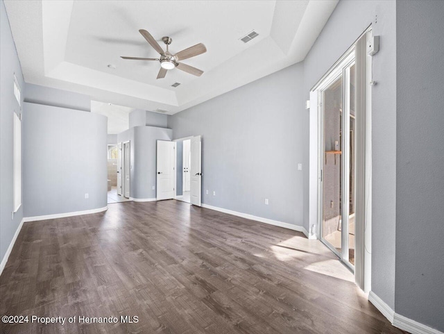 unfurnished room featuring ceiling fan, a raised ceiling, and dark wood-type flooring