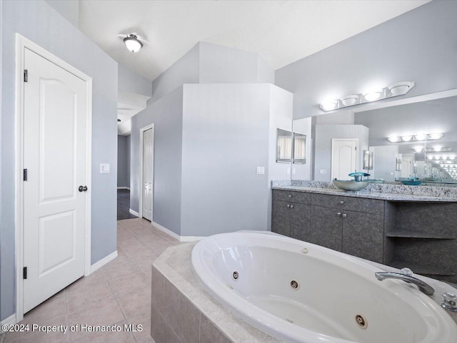 bathroom with vanity, tile patterned floors, vaulted ceiling, and tiled tub