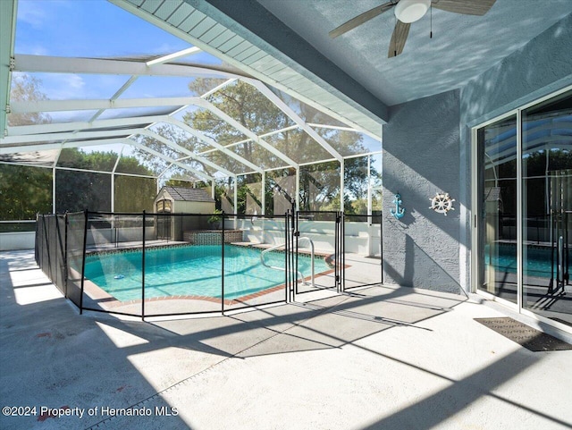 view of pool featuring a lanai, ceiling fan, a storage unit, and a patio area