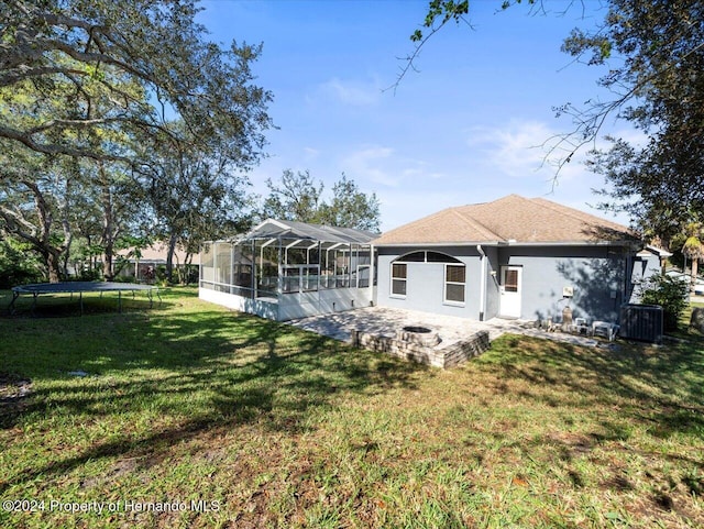 rear view of property with a lanai, a patio area, a yard, and a trampoline