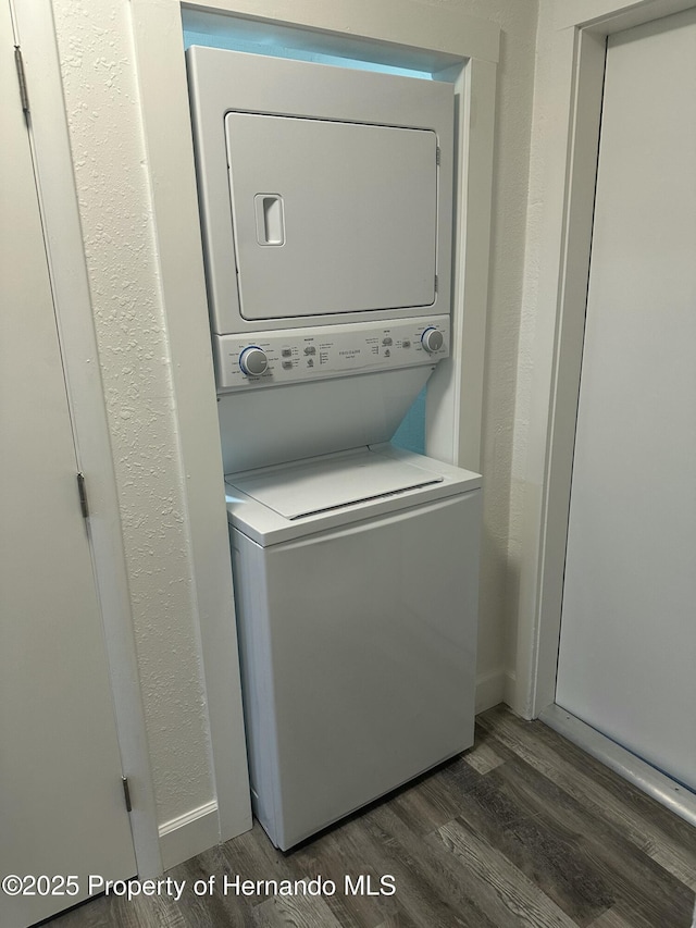 laundry room with stacked washer / drying machine and dark hardwood / wood-style floors