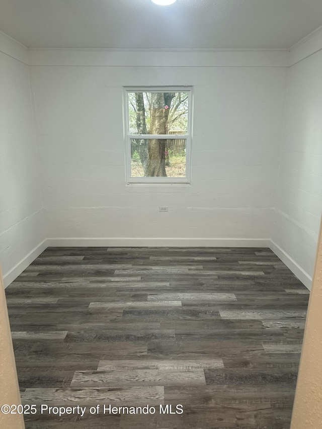 empty room with dark hardwood / wood-style flooring and ornamental molding