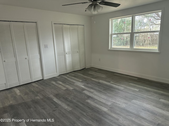 unfurnished bedroom with ceiling fan, two closets, and wood-type flooring