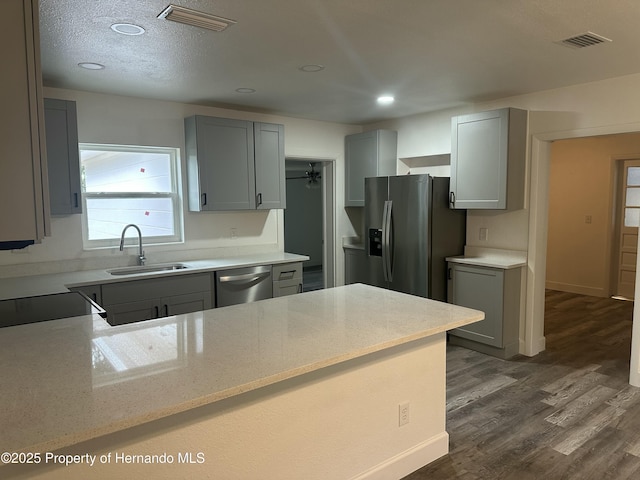 kitchen featuring a textured ceiling, appliances with stainless steel finishes, sink, dark hardwood / wood-style floors, and gray cabinets