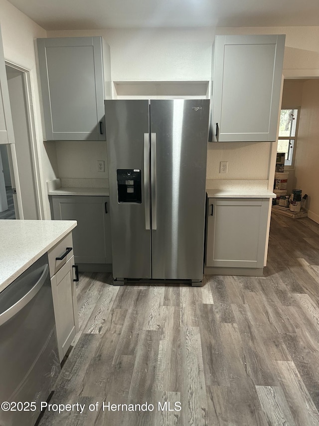 kitchen with white cabinets, appliances with stainless steel finishes, and light wood-type flooring