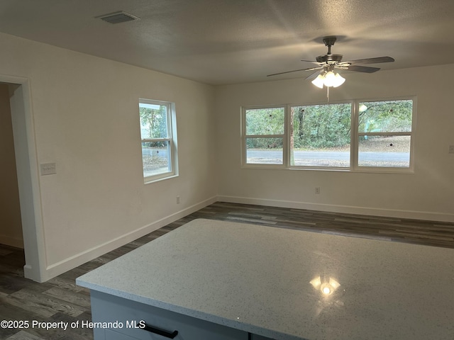 unfurnished room with a textured ceiling, ceiling fan, and dark hardwood / wood-style floors