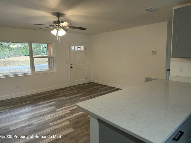 kitchen featuring dark wood-type flooring, ceiling fan, gray cabinetry, and light stone countertops