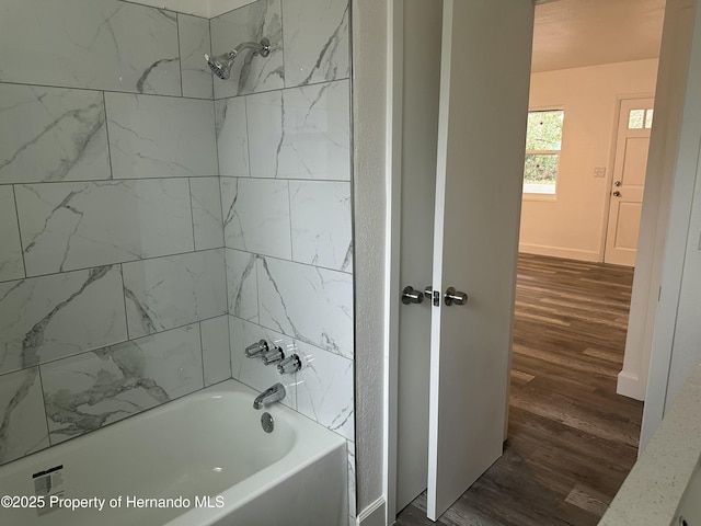 bathroom featuring wood-type flooring and tiled shower / bath