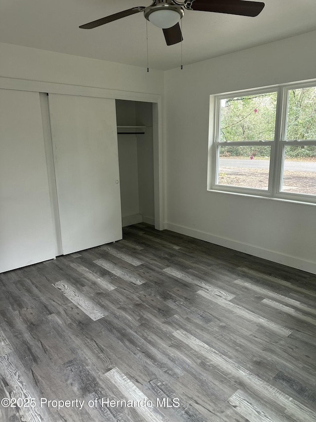 unfurnished bedroom with ceiling fan, a closet, and dark wood-type flooring