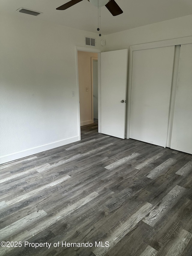 unfurnished bedroom featuring dark wood-type flooring, ceiling fan, and a closet