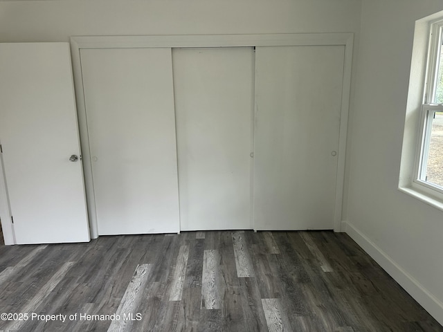 unfurnished bedroom with dark wood-type flooring and a closet