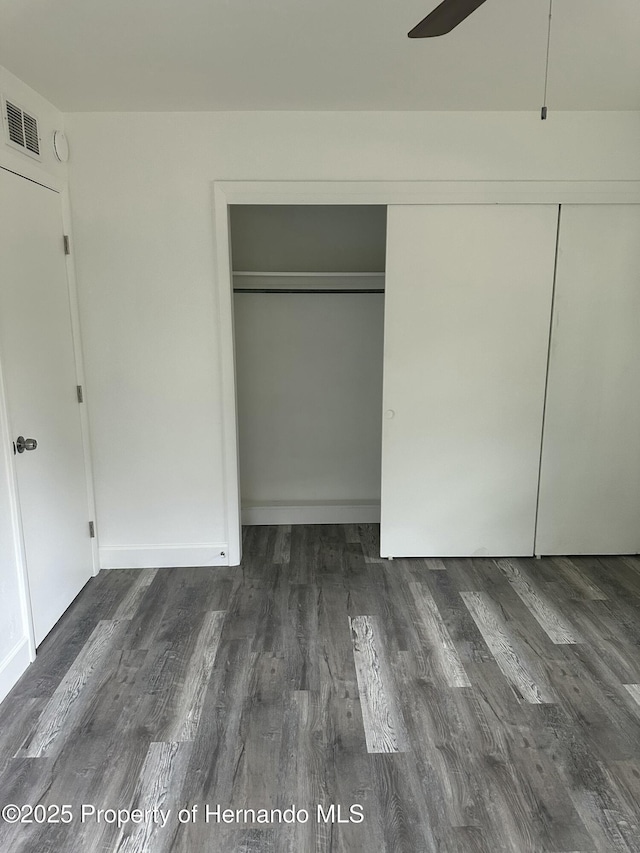 unfurnished bedroom with ceiling fan, dark hardwood / wood-style floors, and a closet