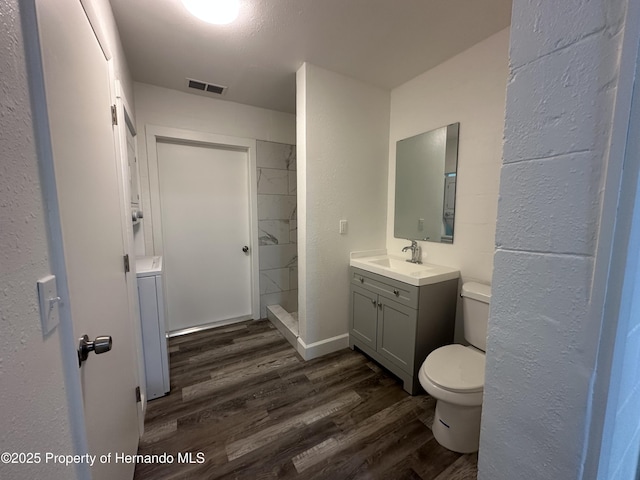 bathroom with toilet, vanity, walk in shower, washer / clothes dryer, and wood-type flooring