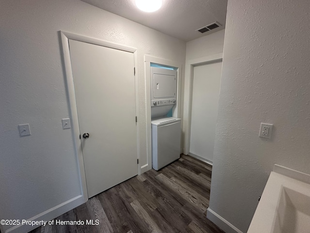 laundry area with dark wood-type flooring and stacked washer and dryer