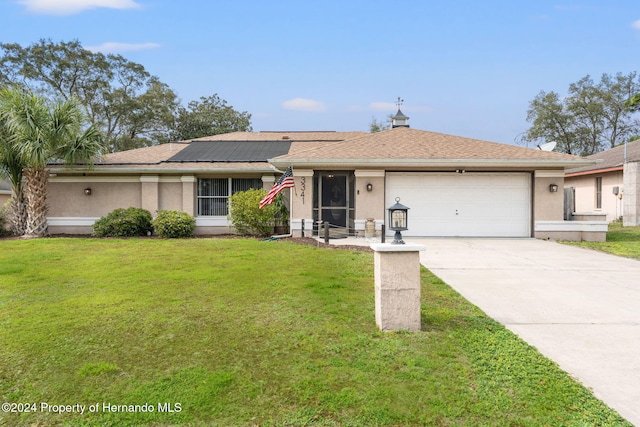 ranch-style home with solar panels, a front yard, and a garage