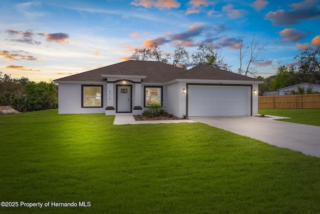 view of front facade featuring a garage, concrete driveway, fence, a yard, and stucco siding